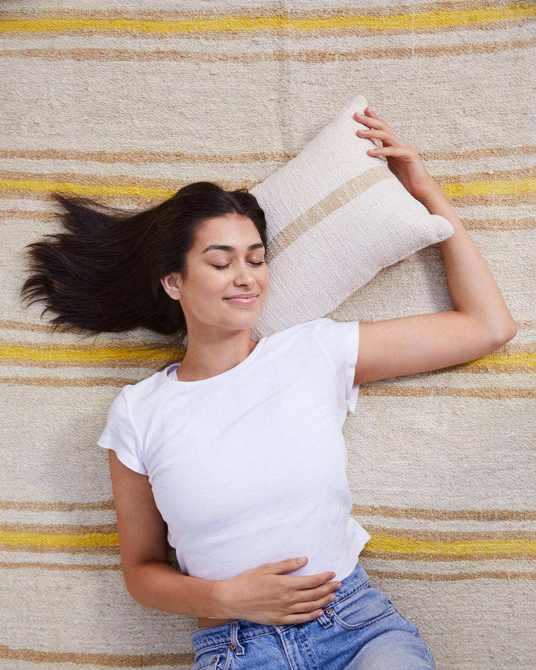 woman laying on striped rug with lumbar pillow